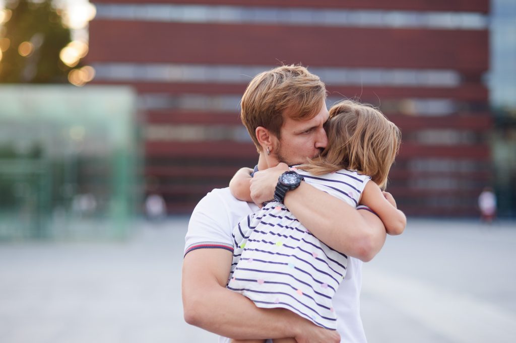 Young father holds the little daughter on hands. Man gently presses to himself the child.